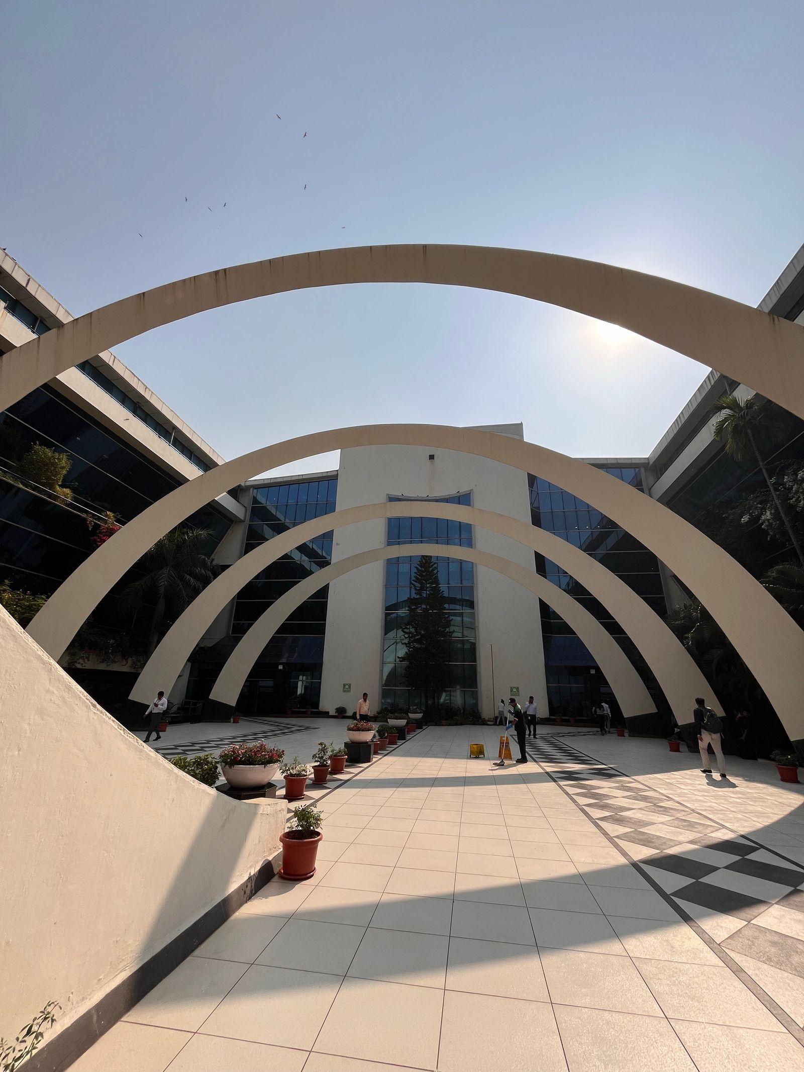 A commercial campus courtyard framed by concentric concrete arches.