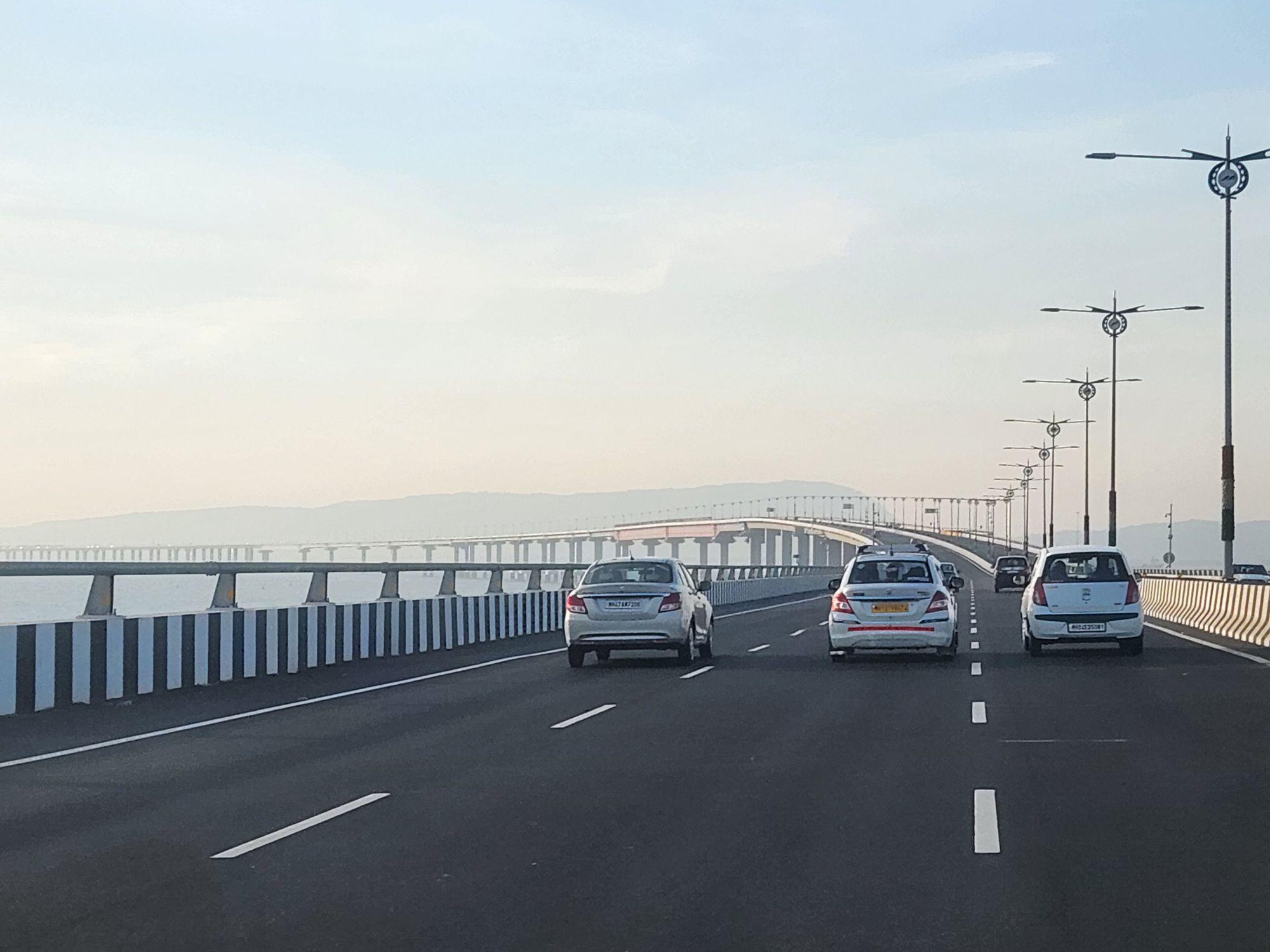 Cars driving across the Atal Setu sea bridge, street lamps lining the deck.