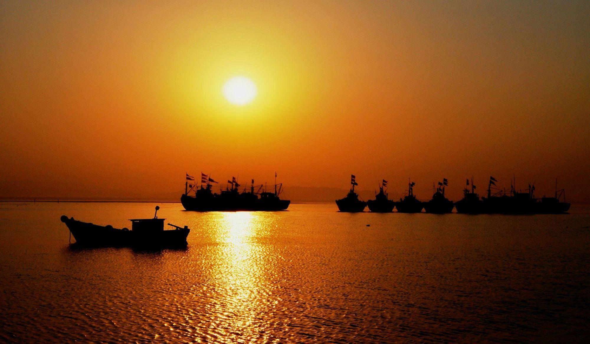Sunrise over the water at Karanja, Uran, with fishing boats silhouetted.