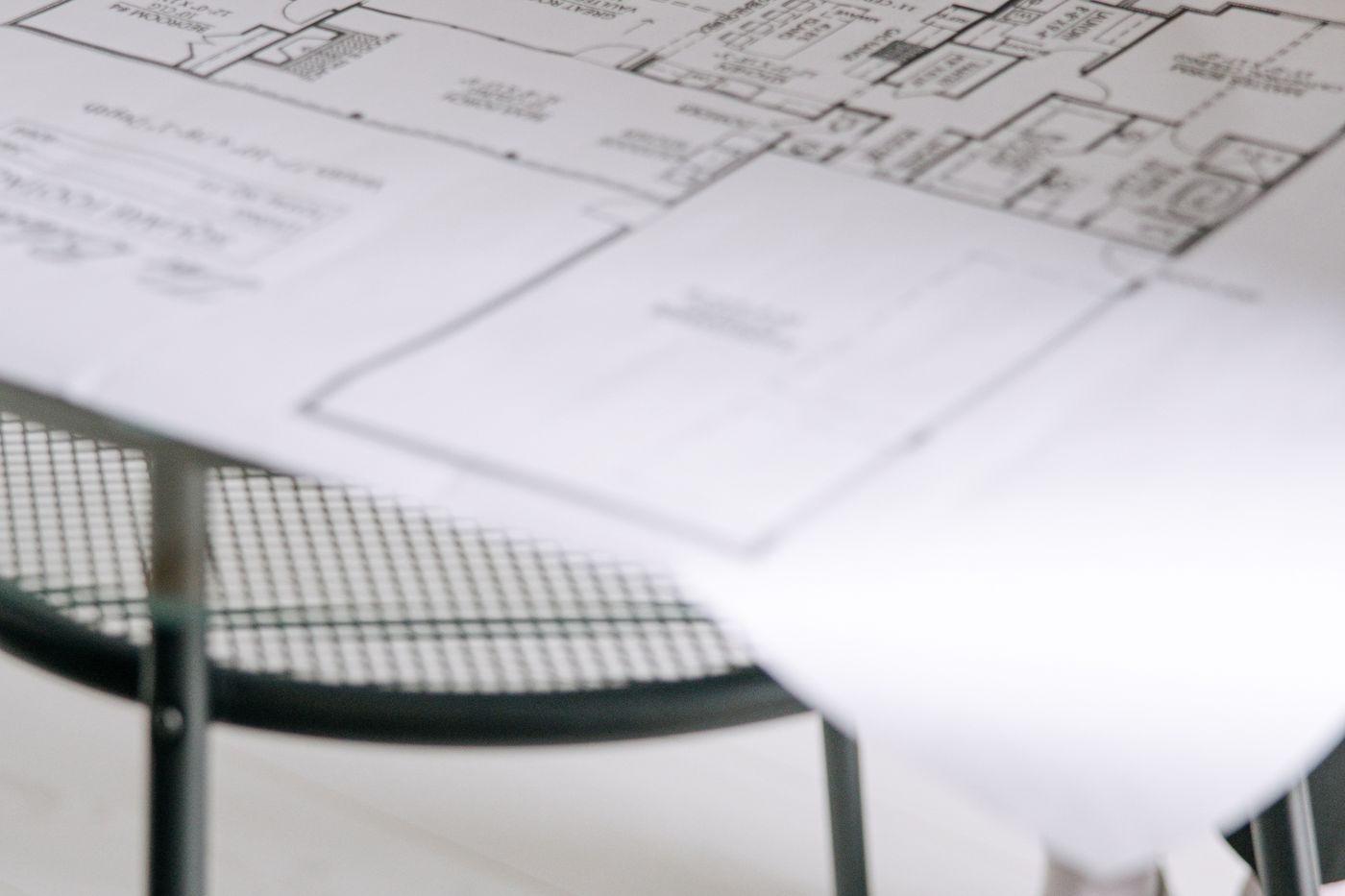 A large floor plan drawing unrolled across a table.