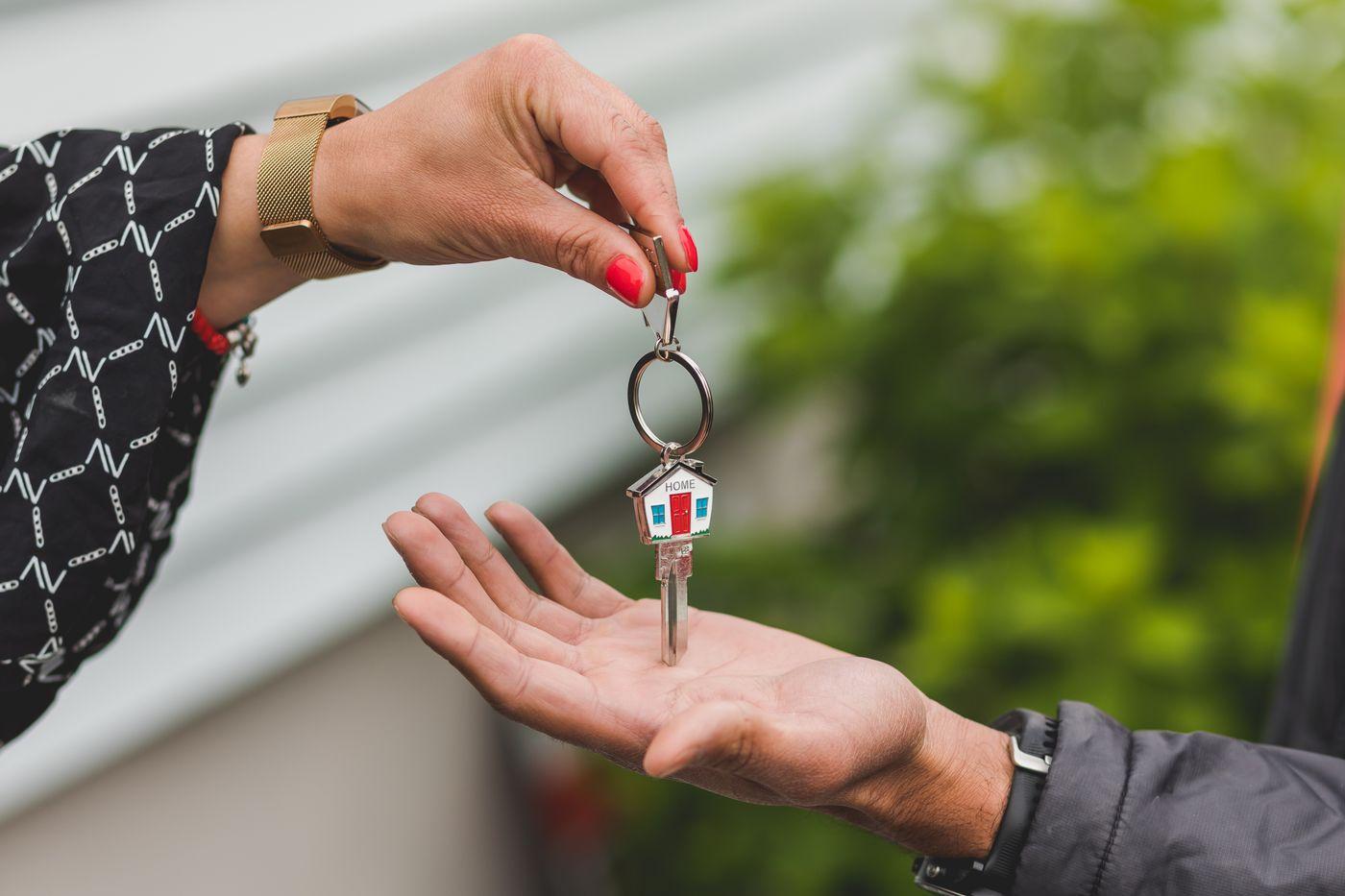 A house key being handed from one person to another.