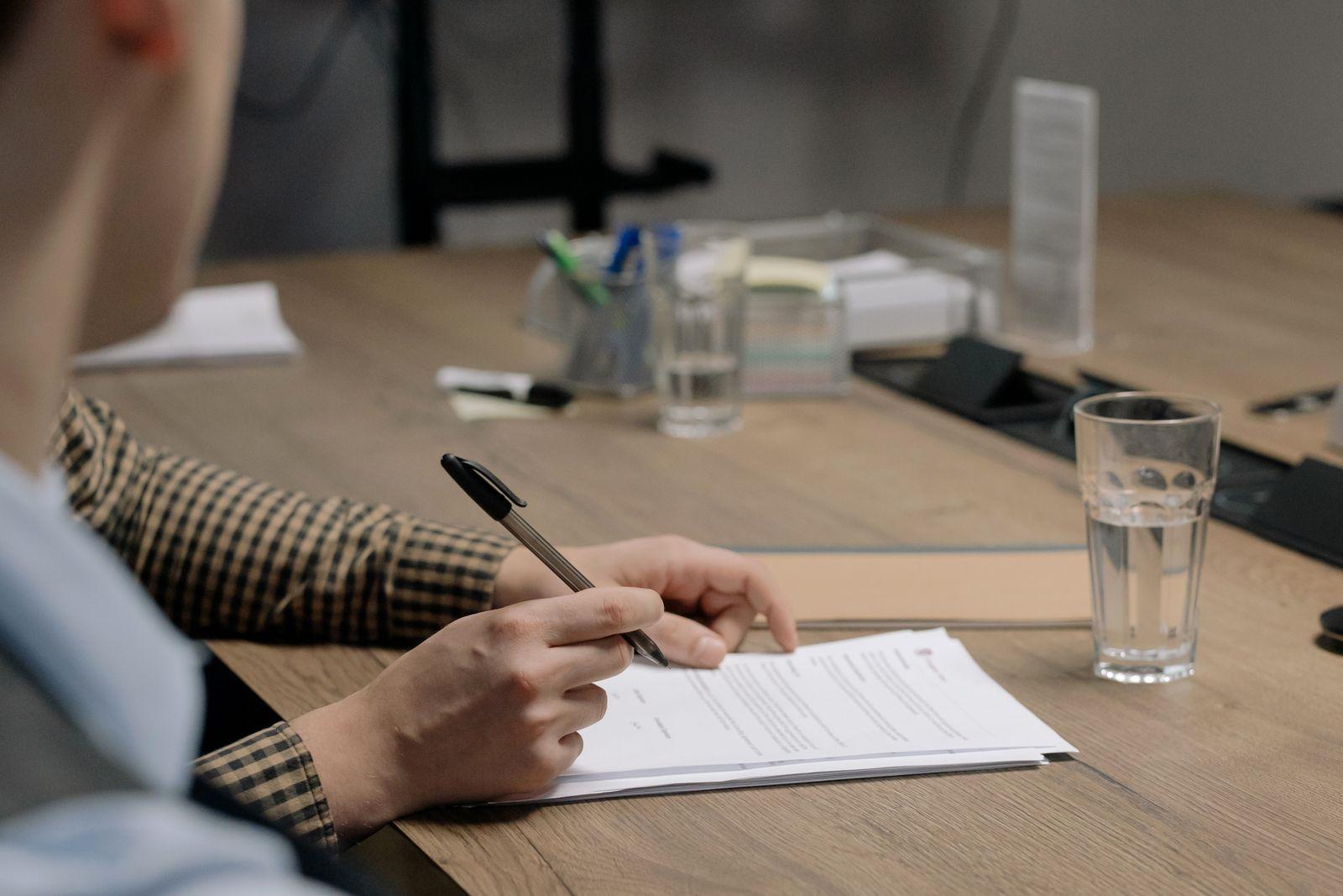 A buyer signing a document across a meeting-room table.