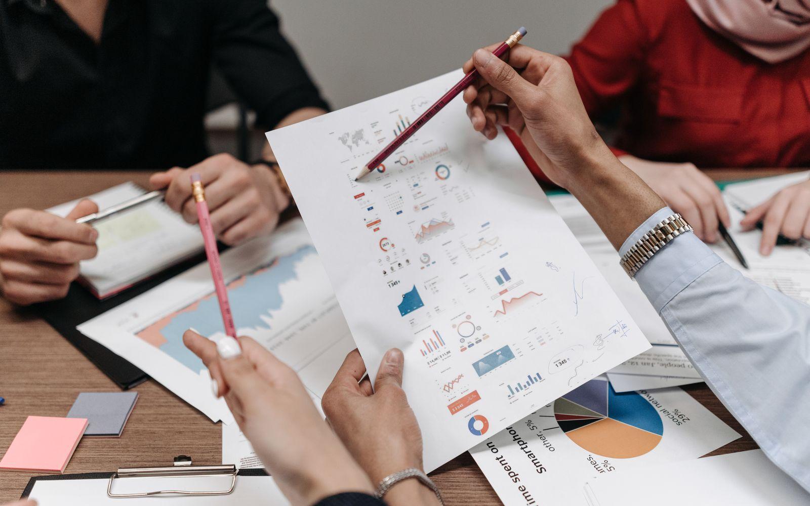 Advisers comparing printed charts and figures across a table.