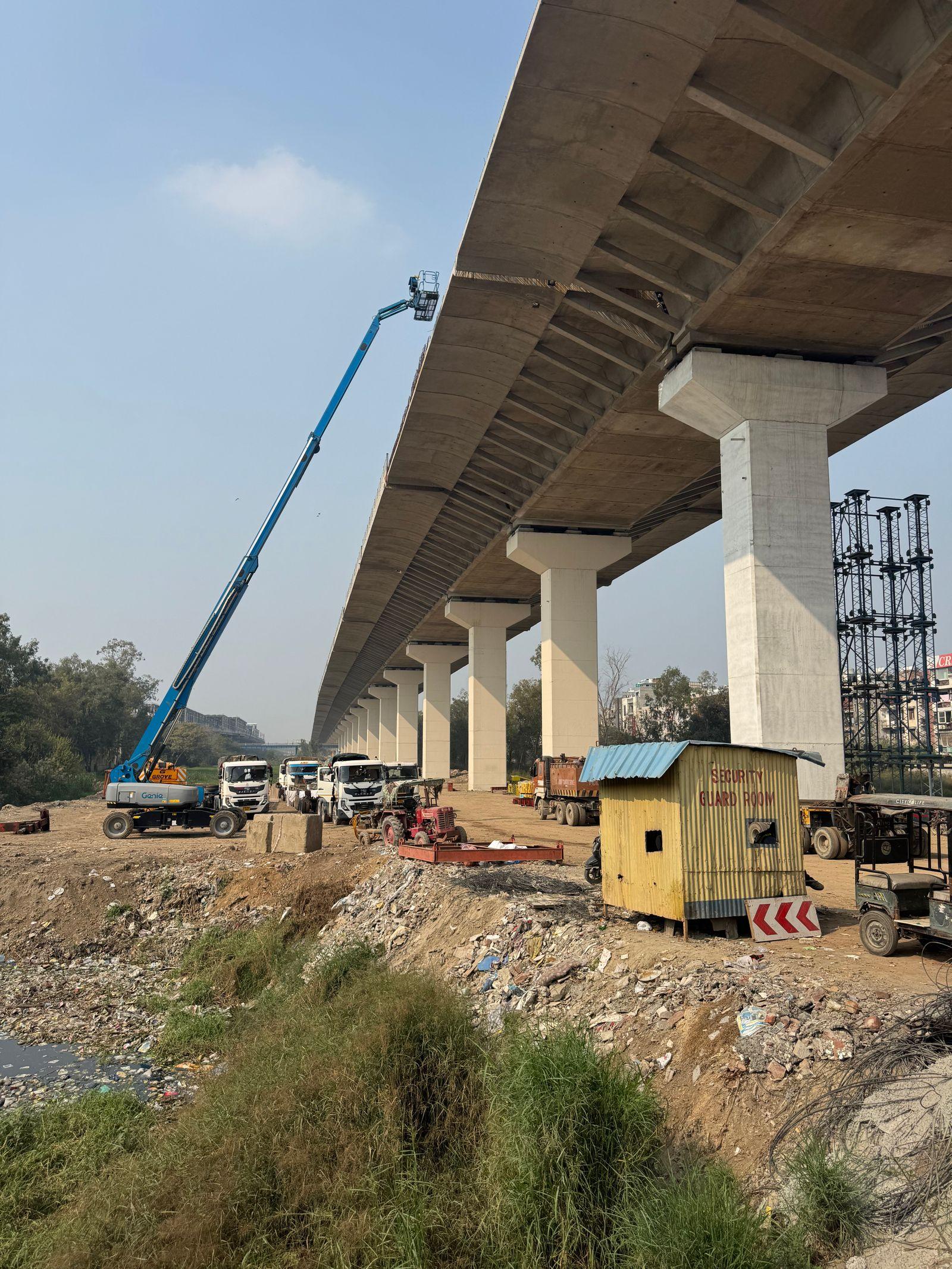 An elevated expressway under construction, with piers, trucks and a lift.
