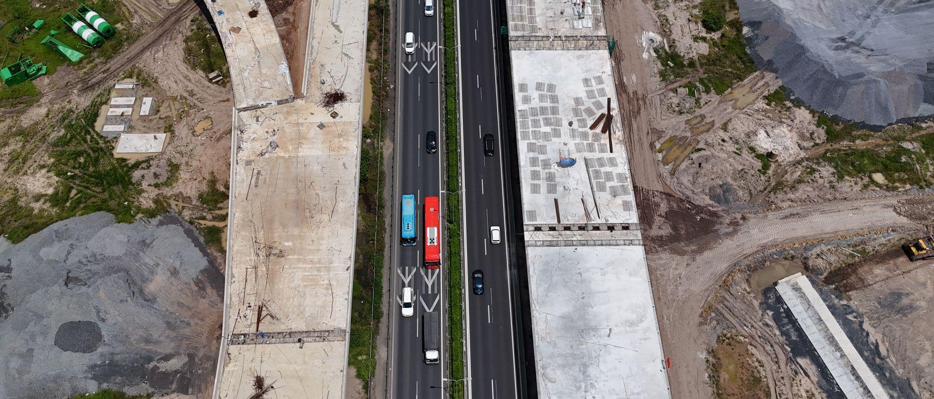 An overhead view of a highway with a flyover under construction alongside.