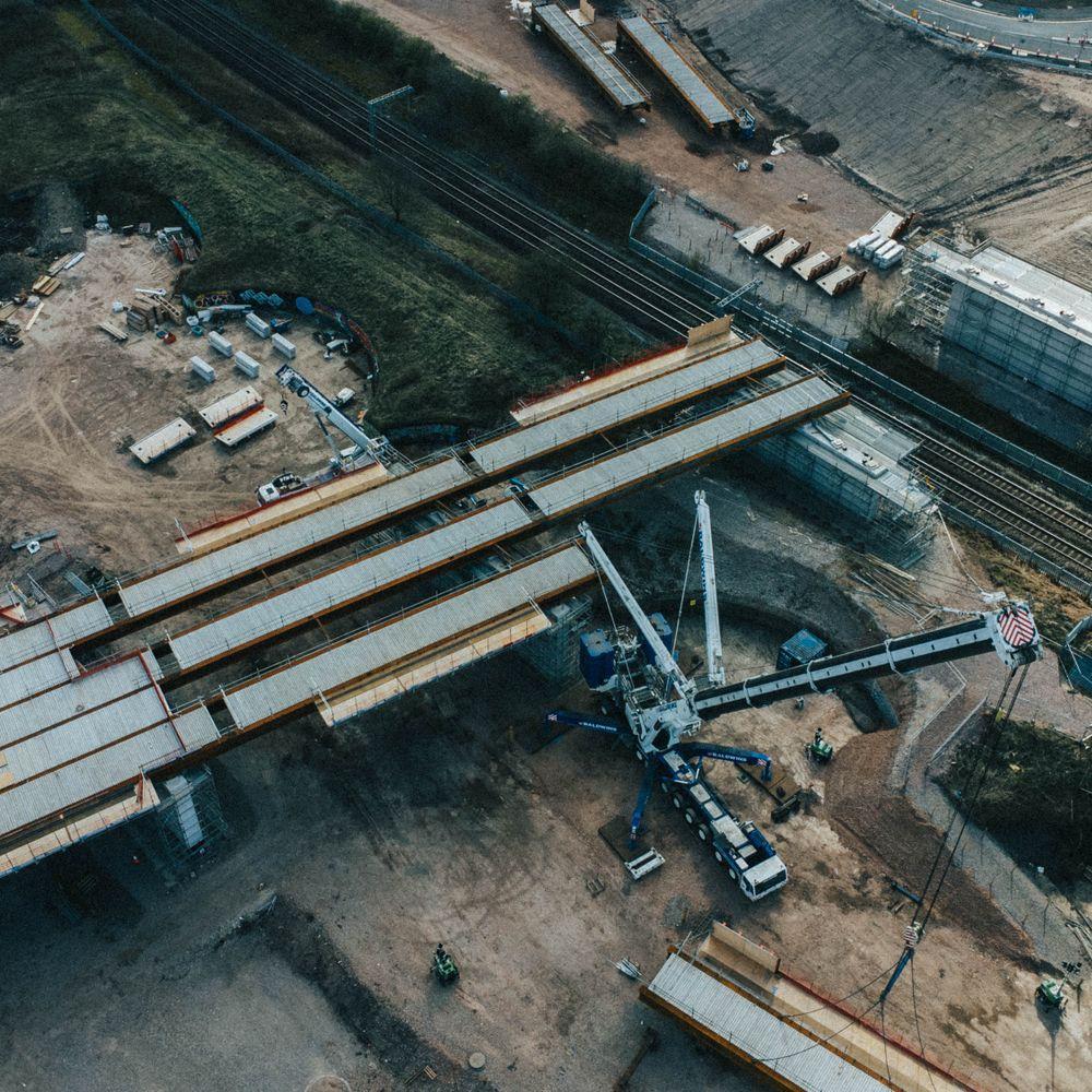 An aerial view of a road bridge under construction beside railway lines.