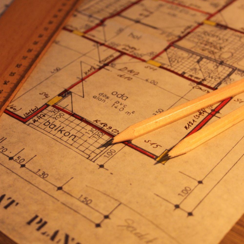 A dimensioned floor plan drawing under a ruler and two pencils.